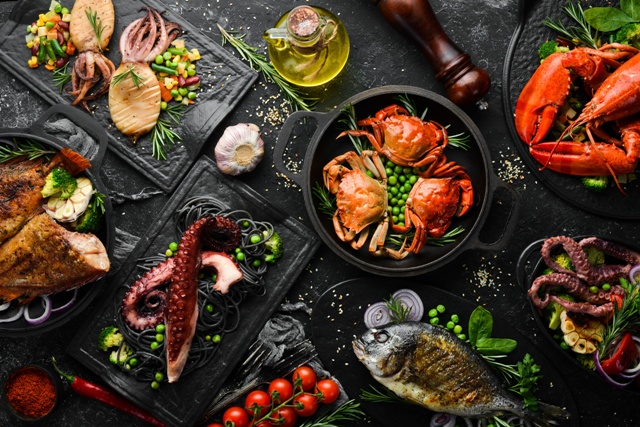 Set of seafood dishes. Fish, squid, octopus on a black stone background. 